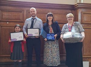 Mr Heade holding a certificate with Linda James, one of his students and another woman